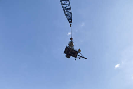 Augusta, Ga USA - 05 15 21: Road construction site machine hanging from a crane boom