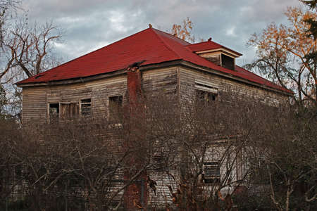 Old creepy scary wooden overgrown abandoned mansion in rural Georgiaの写真素材
