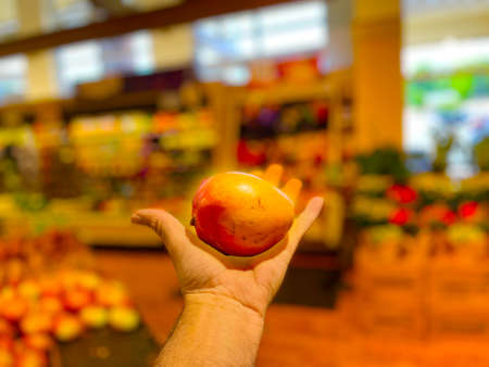 Grovetown, Ga USA - 05 10 22: Retail store produce hand holding an appleの写真素材