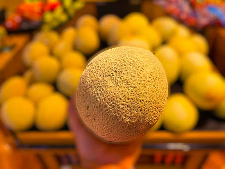 Grovetown, Ga USA - 05 10 22: Retail store produce hand holding colorful cantaloupe effect