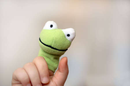 A green frog on a finger of a childの写真素材
