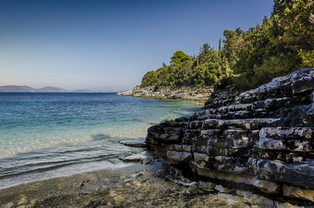 close-up of beach and calcareous rocks in a small and peaceful cove on the route and in the vicinity of the fiskardo village the turquoise sea in the background the mountains of kefalonia islandの写真素材