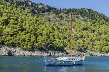 close-up of sailing boat in the background the mountain covered with vegetation in the Bay of Assos...