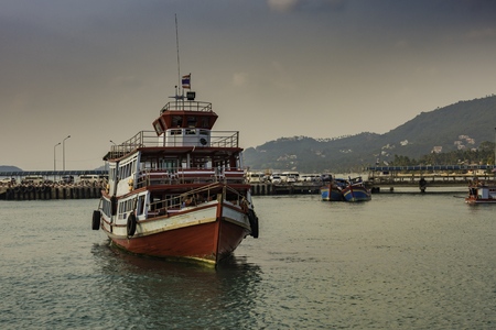 Typical passenger boat on the island of Koh Samui in the gulf of Thailand. Behind are the docks and other colorful small boats and finally the mountains of the island.のeditorial素材