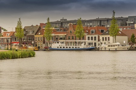 moored boats and old houses in front and new construction back in Alkmaar. netherlands hollandのeditorial素材
