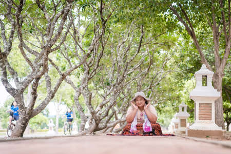 Sukhothai, Thailand-October 20, 2020:  An unidentified woman relax and smile on the pathway in garden of Plumeria plants at Sukhotai Historical Park,  Famous Tourist Destination in Northern Thailandのeditorial素材