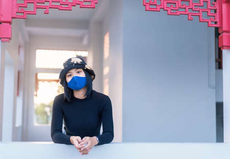 Portrait of young woman wearing protective mask for protection from coronavirus relaxing and thinking of a good time on sunset. Concept of health and safety life COVID-19 coronavirus pandemic outbreakの写真素材