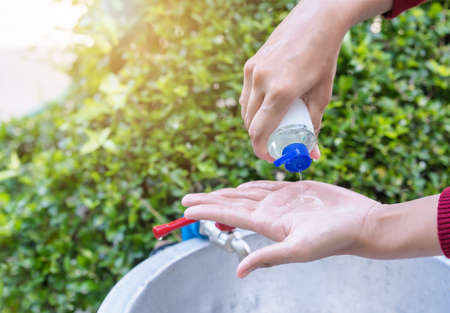 Selective focus on woman hand holding sanitizer bottle and pouring disinfecting alcohol gel to palm of other hand cleaning hands to prevent from covid-19. Coronavirus disinfection conceptの写真素材