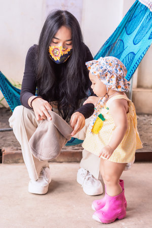 Selective focus on young Asian woman wearing protective mask with cute daughter. Healthcare and social distancing activity for the Covid-19 epidemic conceptの写真素材