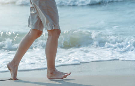 Beautiful healthy female legs jogging with barefoot alone on clean sandy sea beach in ocean in summer morning sunlight. Cute sports woman's legs. Copy space for text. Vacation and lifestyle conceptの写真素材