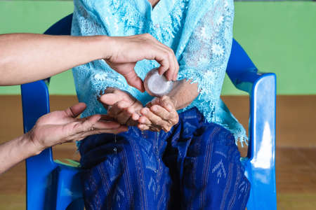 Asian man hands pouring water at hands of elders or mother during  Thai Songkran Festival or Thai New Year. Concept gives blessing and pray respects to elderly in Songkran day, traditions and culture.の写真素材
