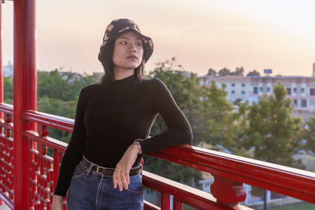 Portrait of happy young woman relaxing on the viewpoint with breathtaking view over city at the terrace with peaceful nature scenery, looking at sunset or sunrise on horizon, copy space for text.の写真素材