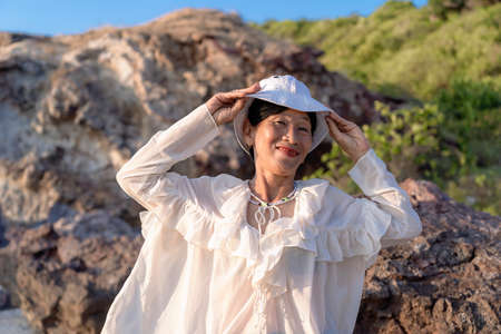 Portrait of a happy mature woman smiling outdoors. Happy smiling mature woman on the rock at sea...
