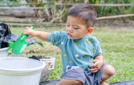 Little child shovels soil into pots to prepare plants for planting. Toddler boy digging soil for planting to Mother's little helper. Gardening. Hobbies at home horticulture. Leisure activities conceptの写真素材