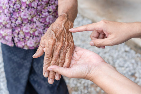 Daughter's fingers points to  wrinkled hand. Aging process - very old senior woman's hands wrinkled skin, effect of age on the skin, old age. wrinkled skin and prominent veins. elderly woman's handsの写真素材