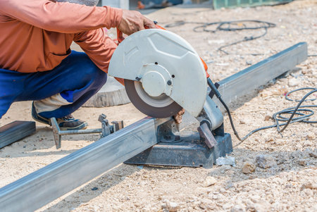 Man's hand using iron cutter in the workplace, fastening iron canopy frame with spark. Worker cutting steel with electric iron cutter. Steel cutter grinder cutting iron pipe with bright sparks.の写真素材