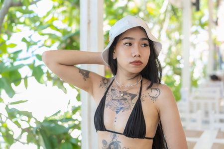 Portrait of pretty girl with slim tanned sexy body in black bikini and beautiful tattoo enjoying life on the beach of tropical island. Vacations and holidays.Summer lifestyle.の写真素材