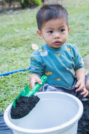 Little child shovels soil into pots to prepare plants for planting. Toddler boy digging soil for planting to Mother's little helper. Gardening. Hobbies at home horticulture. Leisure activities conceptの写真素材