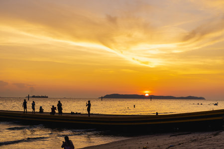 Pattaya, Thailand - June 13, 2023: Silhouette tourists on the beach against the sky during sunset. Beautiful sea in twilight time. Sun setting on the horizon for freedom and beginning life concept.の写真素材