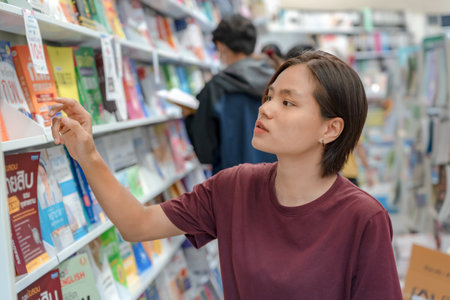 Sakon Nakhon, Thailand-August 5, 2023: Unidentified happy young woman woman shopping and choosing books in the bookstore.の写真素材