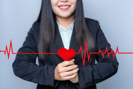 Asian businesswoman holding red heart with red pulse line Heart rate is a line showing the heart's rhythm. cardiovascular disease healthcare 
medical concept Heart disease and insurance conceptsの写真素材