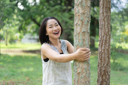 Happy young woman looks cheerful and relaxed in a quiet environment in the middle of a garden. Summer time. Spending time in nature. Maintaining a healthy lifestyle happy lifestyle.の写真素材
