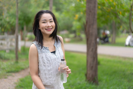 Happy young woman holding a water bottle in her hand Her cheerful demeanor and relaxed demeanor...