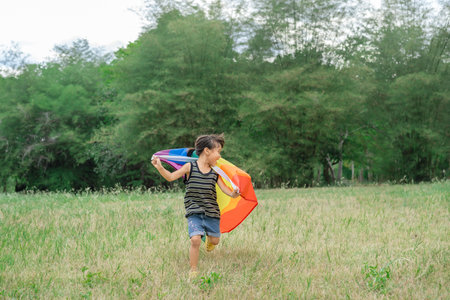 Happy little child holds a rainbow flag, a symbol of inclusivity regarding gender identity. It represents diversity and acceptance. The flag flutters in the wind. Supporting the LGの写真素材