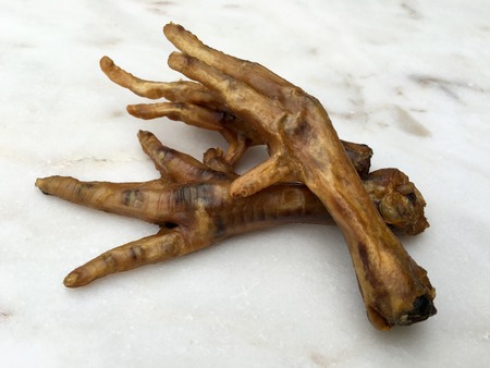 Dried chicken feet on a white marble plate, food for dogsの写真素材