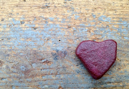 Lonely red heart made of stone on old woodの写真素材