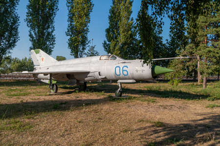 Supersonic aircraft MIG 21. Combat fighter installed in the Victory Park of Nizhny Novgorod on the ground, surrounded by trees and against the sky. High quality photoの写真素材