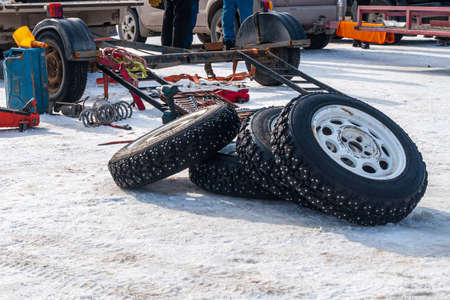 Spare wheel with tools and canisters. High quality photo Studded wheel lies on the snow next to the tool box and red fuel canistersの写真素材