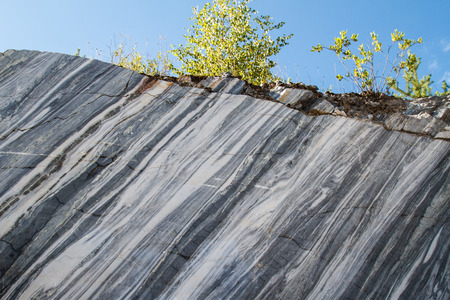 Marble quarry, marble rocks in the wild in the Republic of Karelia. Natural stone. Ancient Marble quarry, marble rocks in the wild. Slices of marble mountain. Trees on the marble rock. Historic place.の写真素材