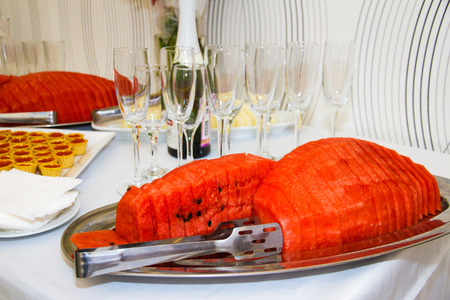 Sliced ??watermelon on a dish. Sweet berry on the table. The pink flesh of watermelon for dessert. Healthy food for vegetarians. Festive table setting with fruit and berries.の写真素材