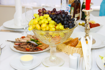 Grapes in a vase on the holiday table. Berries and fruit for Dessert at the party, the Banquet. The food for the Banquet. Holiday. Serving. The table decorations, the Restaurant dish. Service.の写真素材