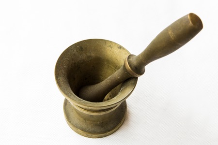 Ancient brass mortar to grind coffee on white table. Elegant classic coffee beans. Heavy metal coffee mortar.の写真素材