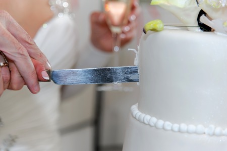 Elderly couple cuts the wedding cake. Marriage of older persons. Couple holding the big knife and cut the cake.の写真素材