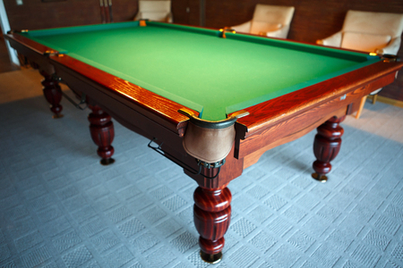 Pool table from natural slate covered with green cloth. The movement of the balls with the cue -...
