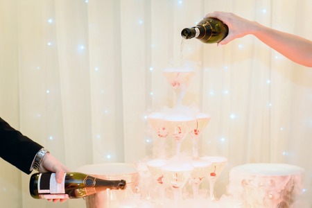 Pouring champagne into glasses of alcohol a holiday party. Service restaurant business.の写真素材