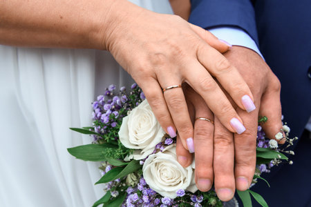 Bride and groom holding hands with wedding bouquet of flowers, closeupの写真素材