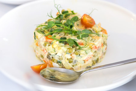Olivier salad in a white plate on a white background.の写真素材
