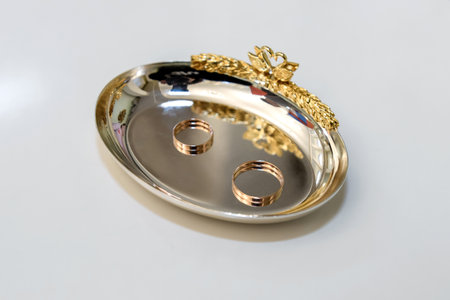 Gold wedding rings on a silver plate on a white background, close-upの写真素材