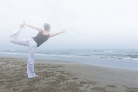 early in the mornig woman practice  healthy yoga on the beach.