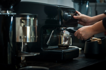 espresso machine with hand in processing coffee drinkの写真素材