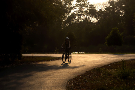 woman driving on bicycle in evening sunny park toned imageの写真素材