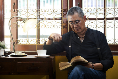 Man reading book and drinking coffee in the morningの写真素材