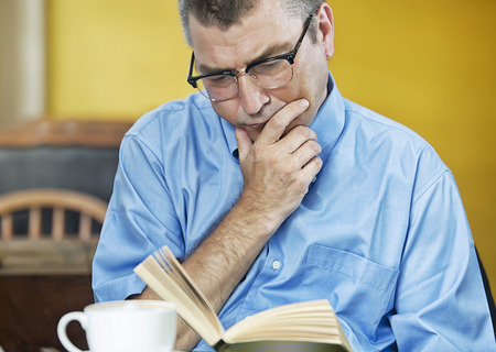 man caucasian reading concentrated in a cafeの写真素材