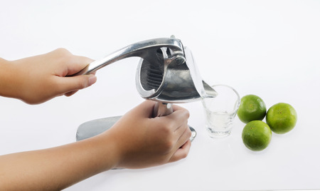 Preparing fresh lemon juice squeezed with stainless juicer on white backgroundの写真素材