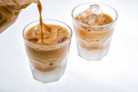 Pouring tea to glass with ice isolated on white background