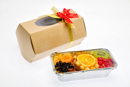 fruit cake and packed gifts with red tapes on white backgroundの写真素材